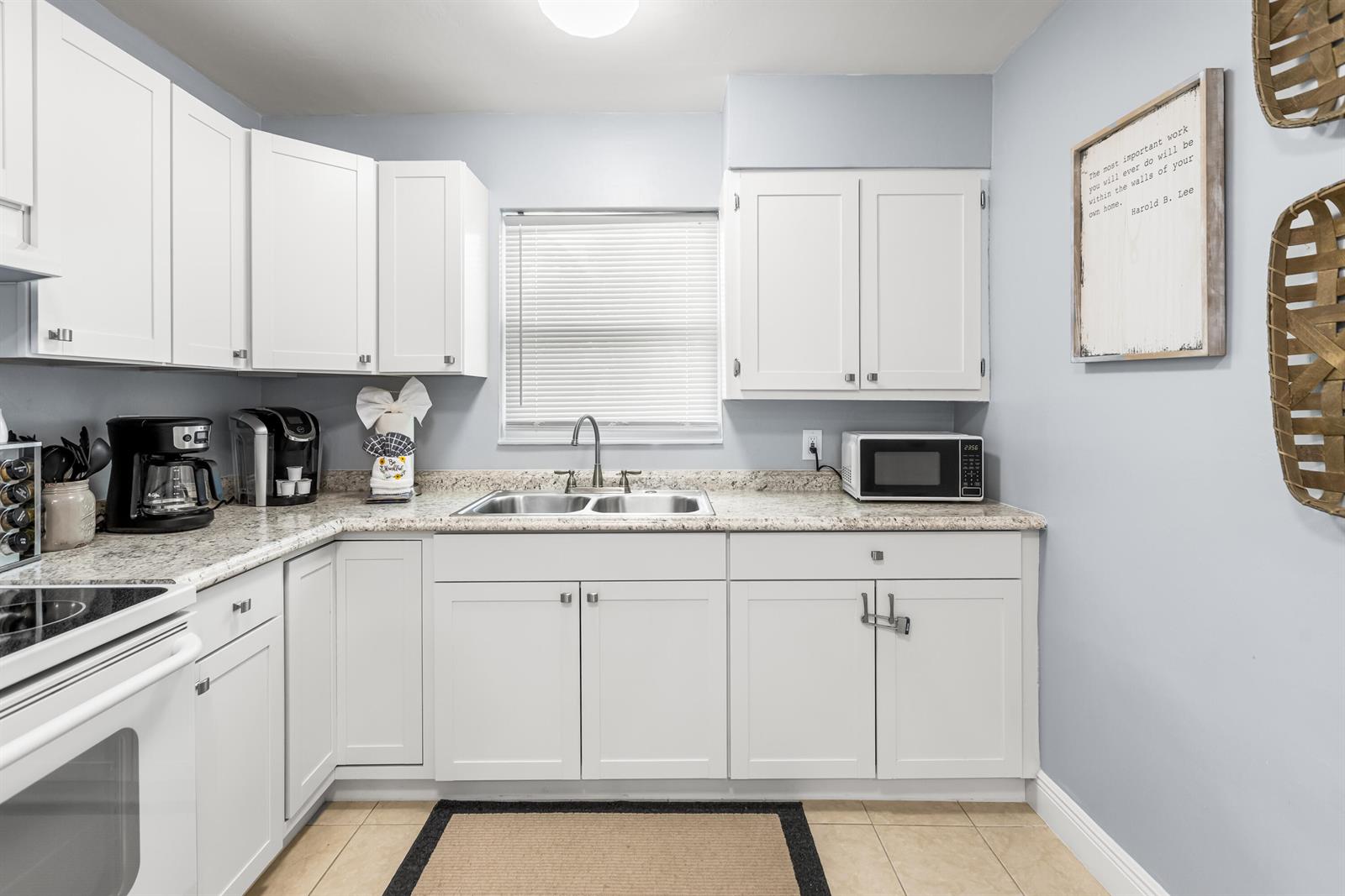 A kitchen with white cabinets, granite countertops, a double sink, and light blue walls — 4953 Bayshore Drive, Naples FL 34112, NAPLES, FL