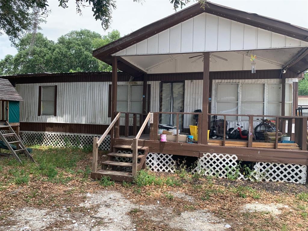 A single-story mobile home with a brown-trimmed exterior, a front porch, and lattice skirting — 11811 HAZEN AVENUE, THONOTOSASSA, FL