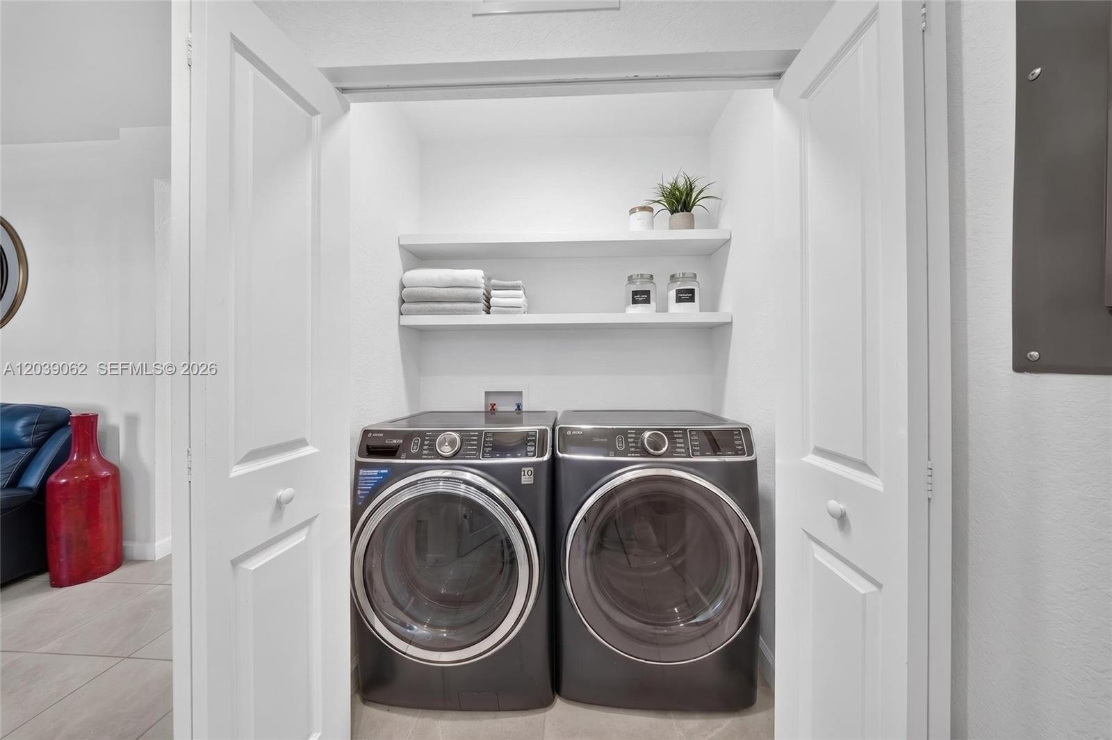 A laundry closet features two dark gray front-load appliances beneath two white storage shelves — 29253 SW 162nd Ct, Homestead FL 33033, HOMESTEAD, FL