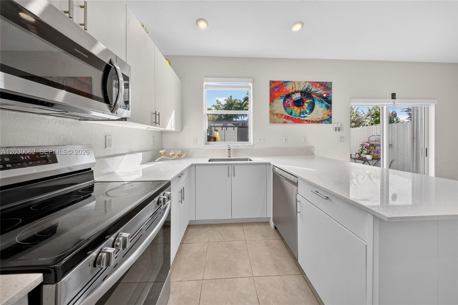 A modern kitchen features white cabinets, stainless steel appliances, quartz countertops, and a colorful eye painting — 29253 SW 162nd Ct, Homestead FL 33033, HOMESTEAD, FL