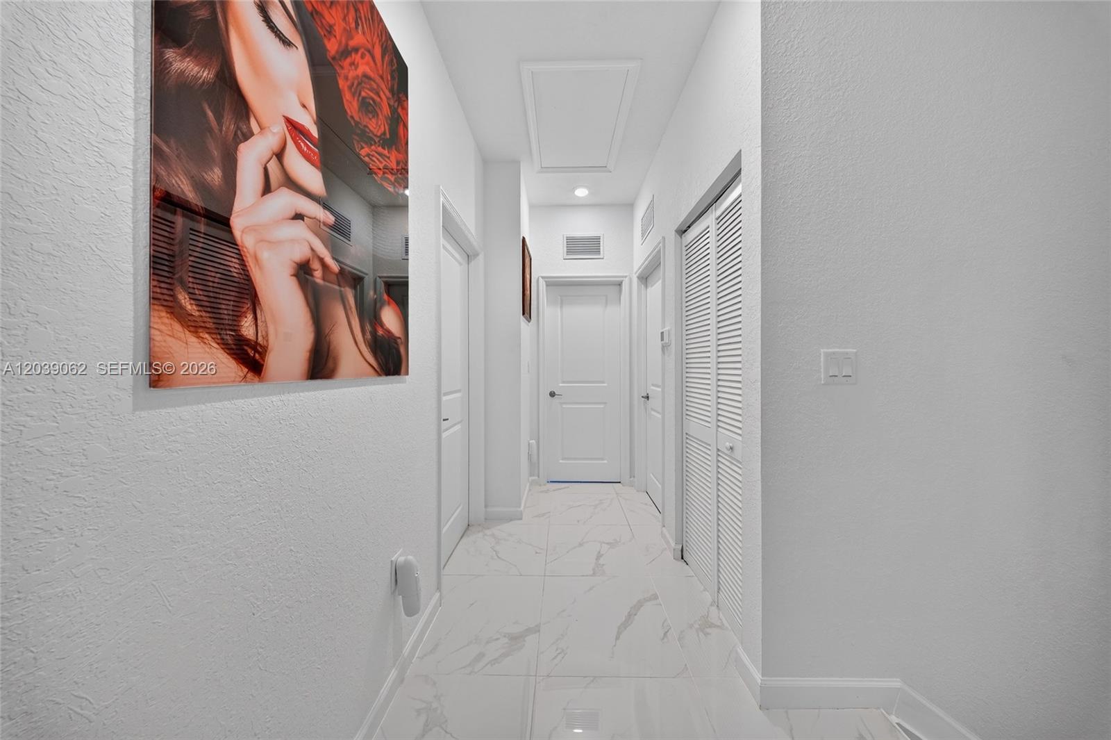 A white hallway features marble-style tile flooring, several closed doors, and a large wall portrait — 29253 SW 162nd Ct, Homestead FL 33033, HOMESTEAD, FL