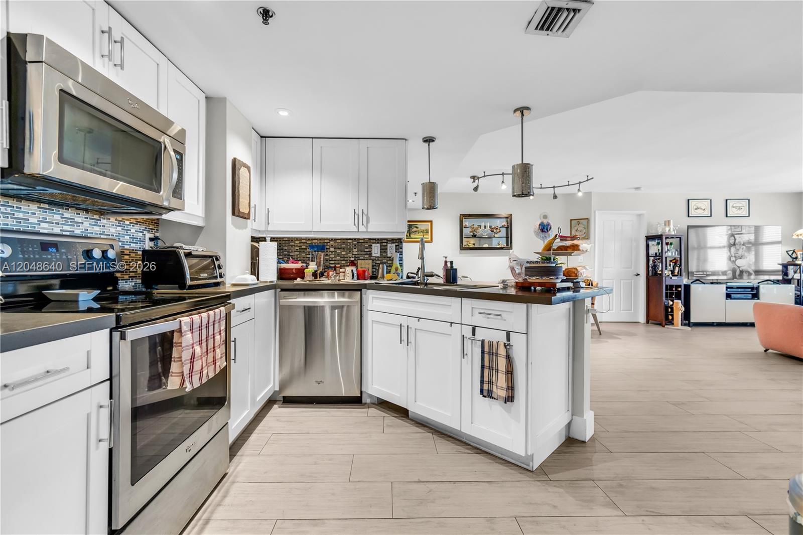 A kitchen with white cabinets, stainless steel appliances, and wood-look tile flooring — 2351 Douglas Rd # 1101, Miami FL 33145, MIAMI, FL