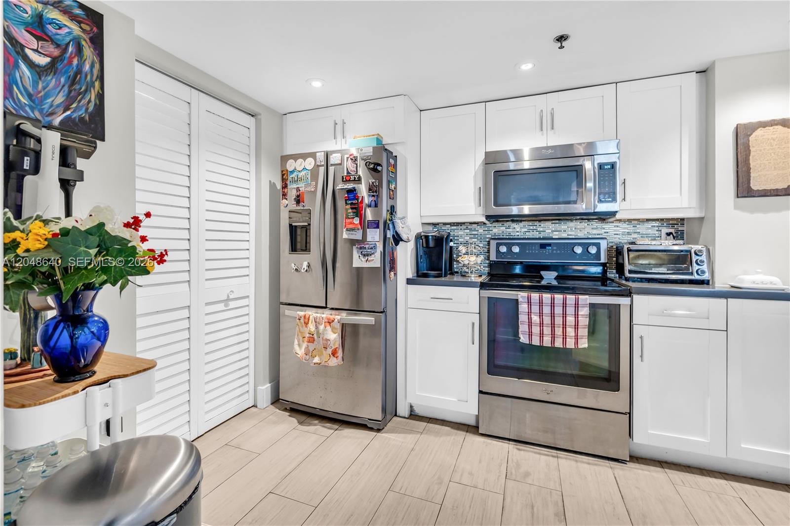 A kitchen features white cabinets, stainless steel appliances, and a tiled backsplash — 2351 Douglas Rd # 1101, Miami FL 33145, MIAMI, FL
