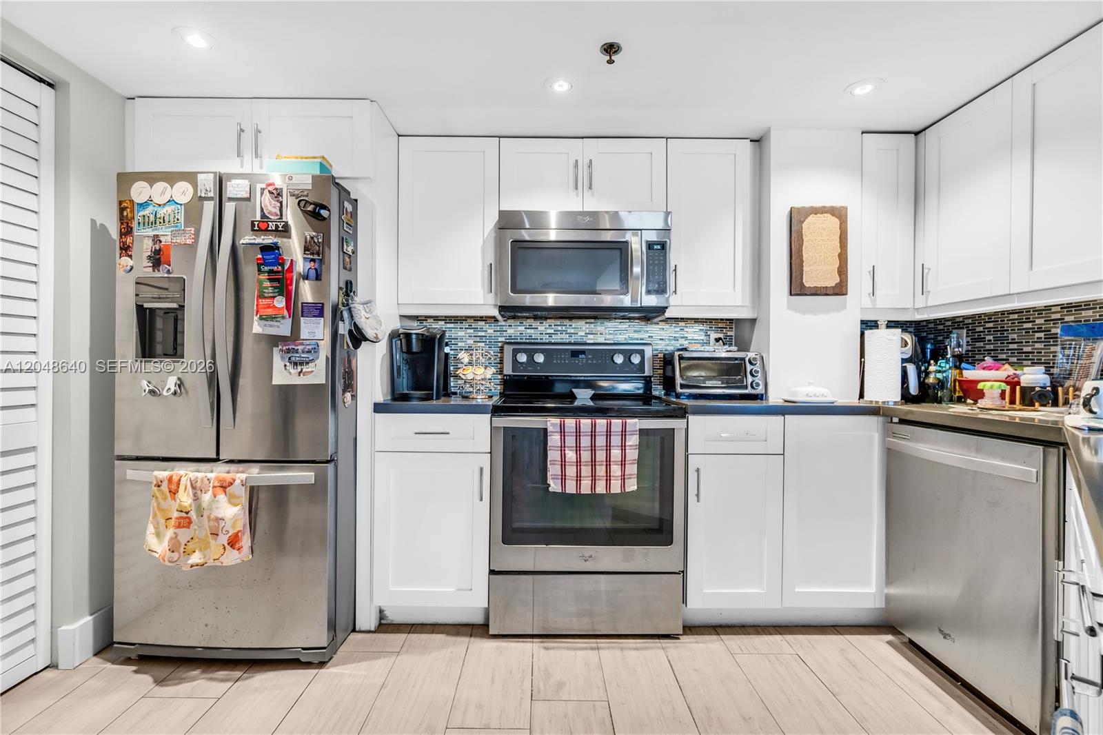 A kitchen features white cabinets, stainless steel appliances, and a tiled backsplash — 2351 Douglas Rd # 1101, Miami FL 33145, MIAMI, FL