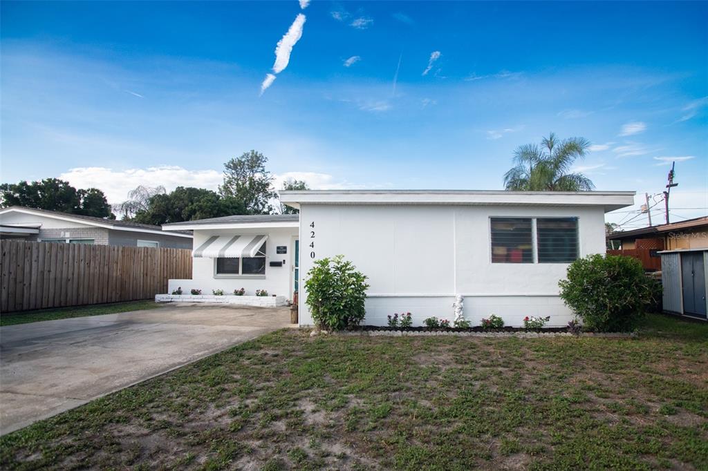 A single-story white house with a concrete driveway, a small front yard, and an awning — 4240 69TH AVENUE N, PINELLAS PARK, FL