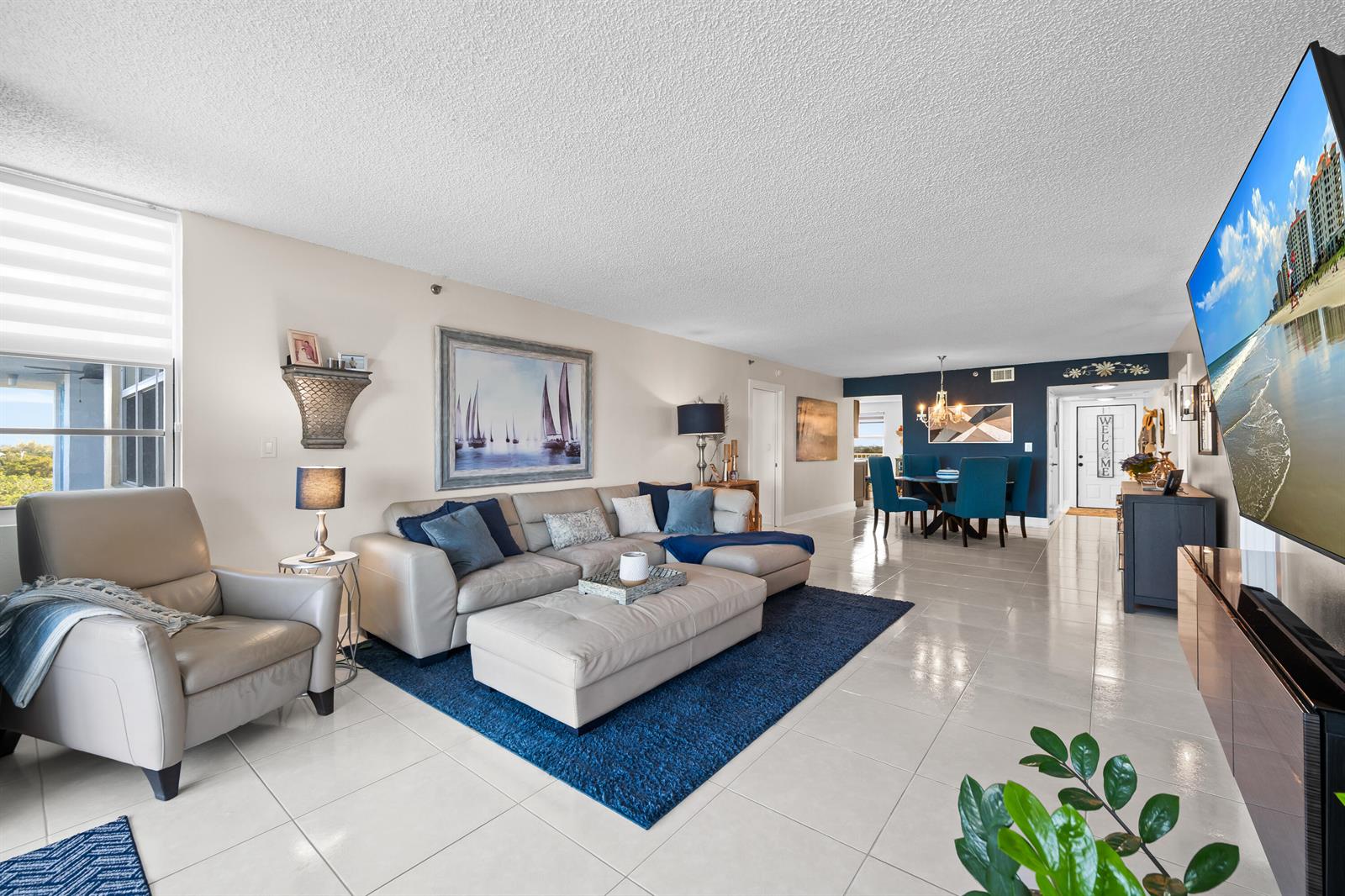 A living room with light tile floors, a sectional sofa, and a dining area beyond — 3095 N Course Drive # 702, Pompano Beach FL 33069, POMPANO BEACH, FL