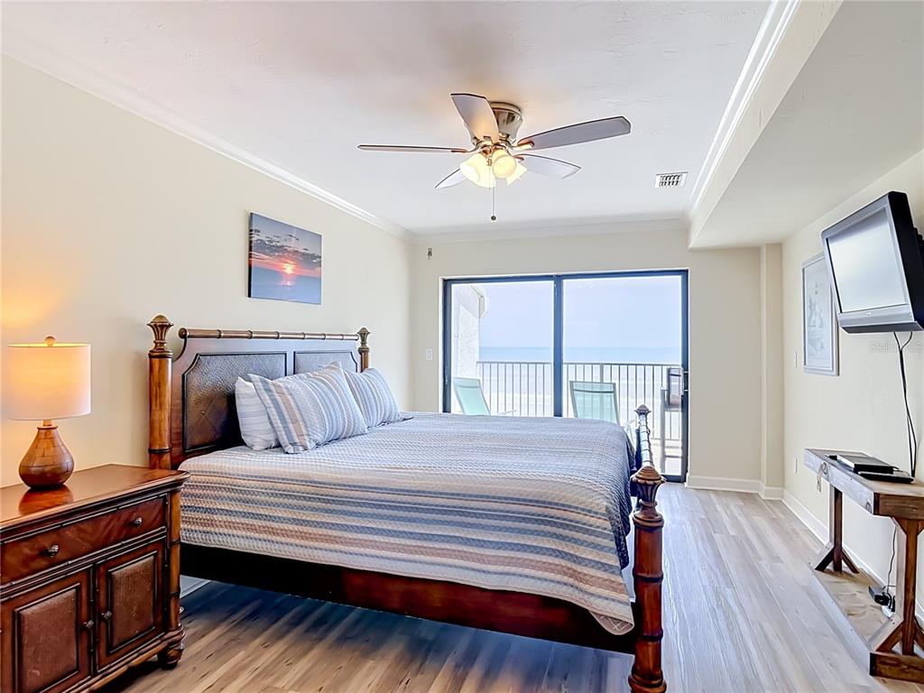 A bedroom features a wooden bed, a ceiling fan, and a balcony overlooking the ocean — 3001 S ATLANTIC AVE UNIT 442, NEW SMYRNA BEACH, FL