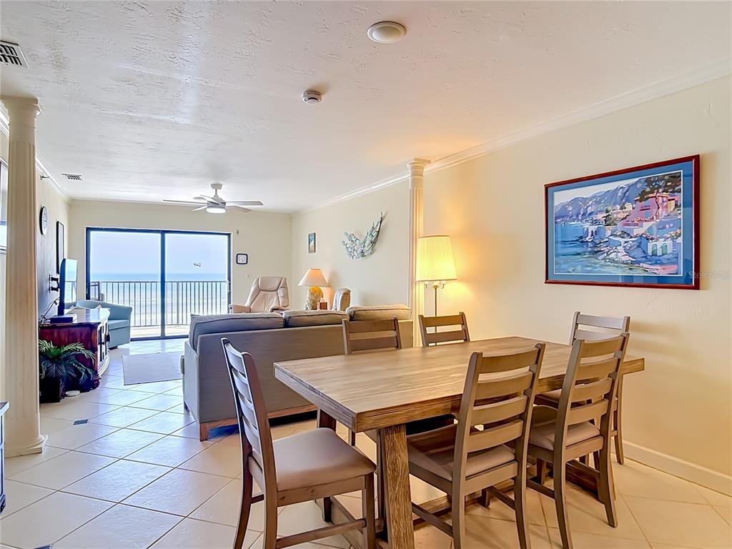A dining area with a wooden table and chairs opens into a living room with ocean views — 3001 S ATLANTIC AVE UNIT 442, NEW SMYRNA BEACH, FL