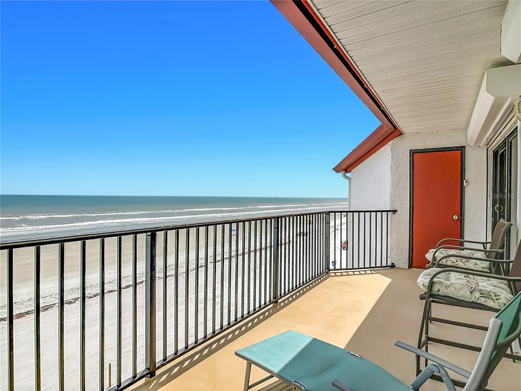 A balcony with a black metal railing overlooks a sandy beach and the ocean — 3001 S ATLANTIC AVE UNIT 442, NEW SMYRNA BEACH, FL