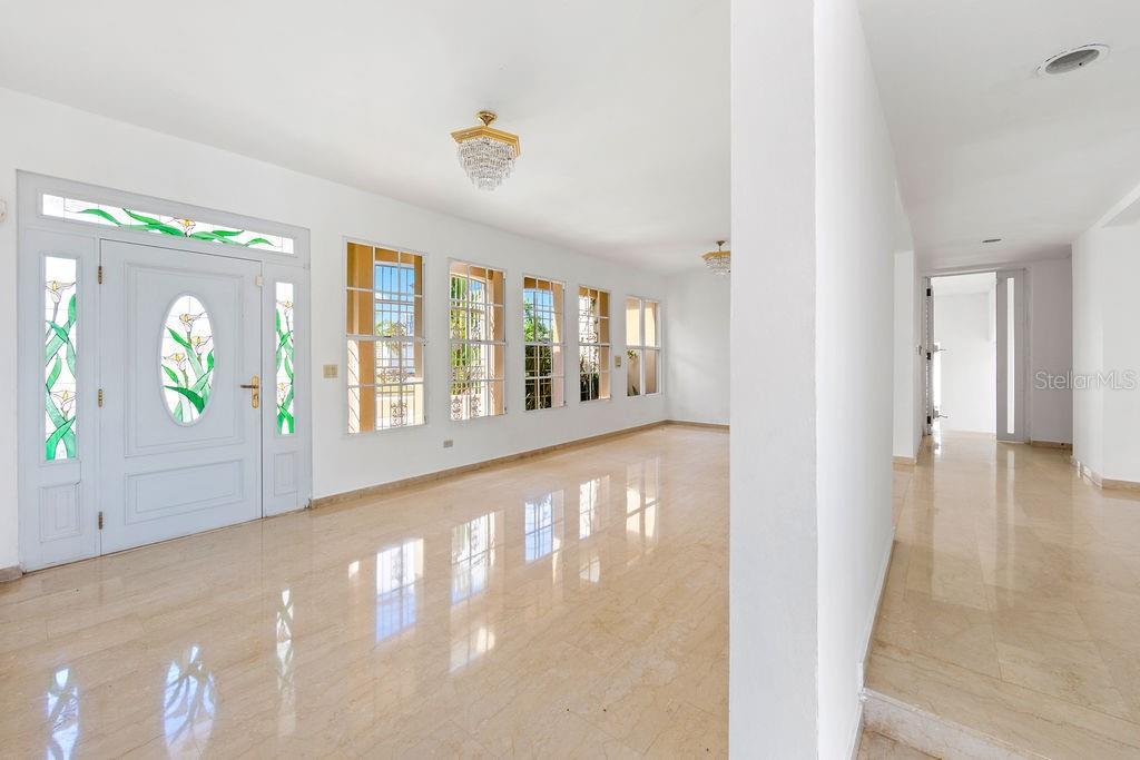 A bright, empty foyer features white walls, marble flooring, a crystal chandelier, and stained-glass doors — URB. SANTA MARIA 1906 CLL ORQUIDEA, SAN JUAN, PR