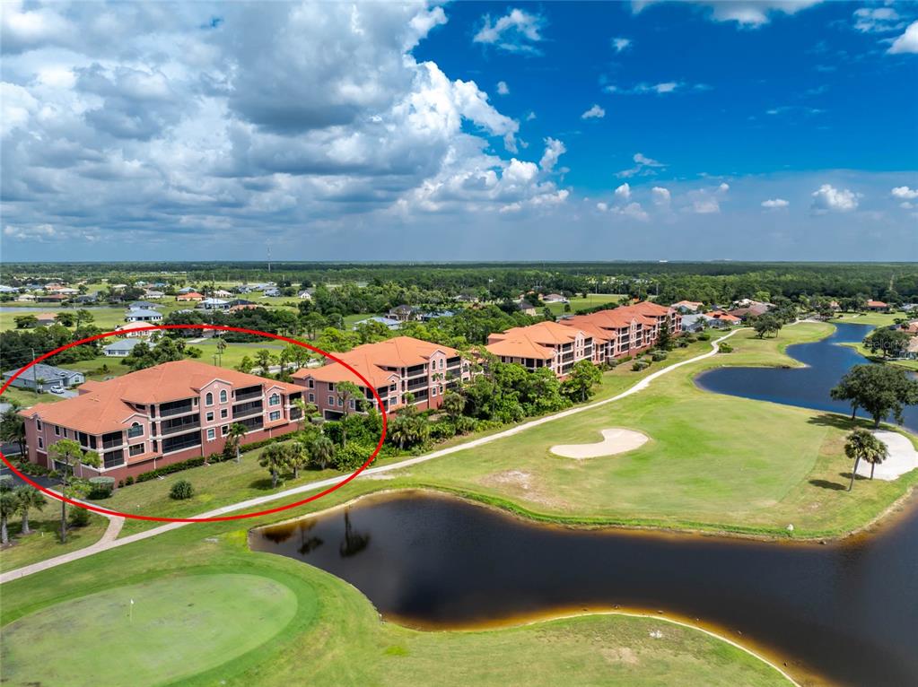 An aerial view shows a multi-story residential building with a red roof near a golf course — 24351 BALTIC AVE UNIT 203, PUNTA GORDA, FL
