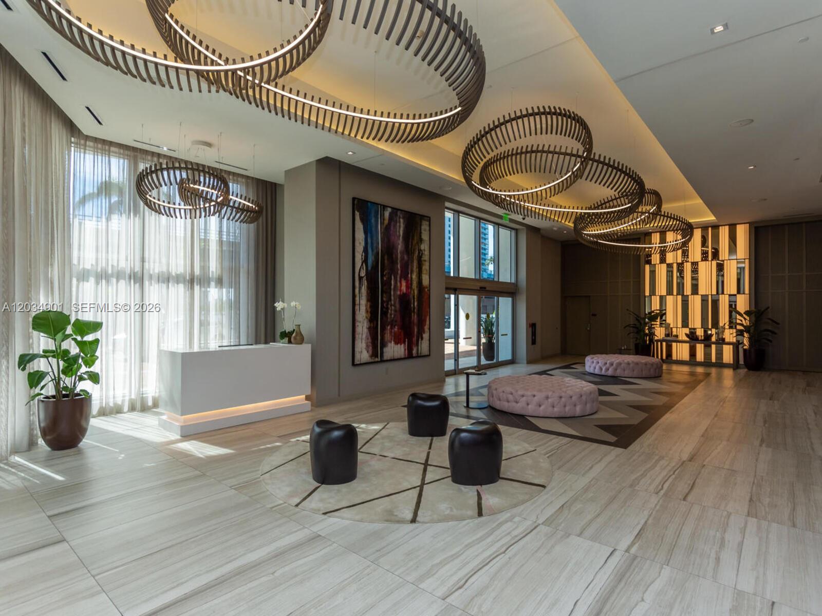 A modern lobby features a white reception desk, circular light fixtures, and contemporary seating areas — 4010 S Ocean Dr # T3705, Hollywood FL 33019, HOLLYWOOD, FL