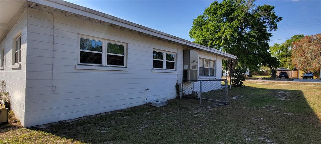 The exterior side of a white house features a window air conditioning unit and fencing — 1540 AVENUE C NE, WINTER HAVEN, FL