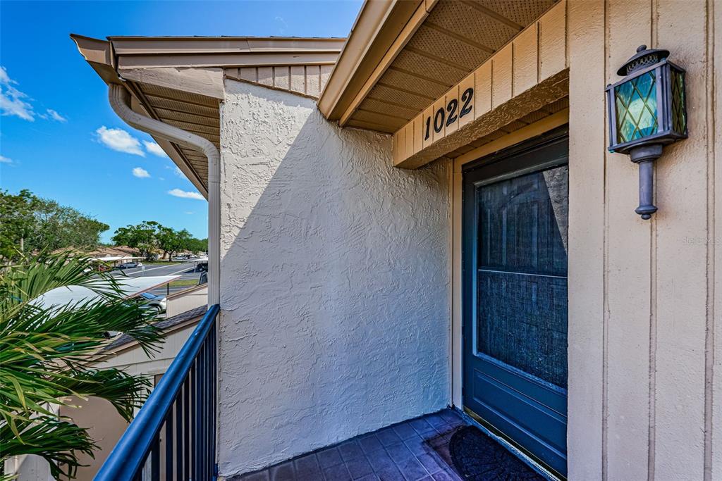 An exterior view of a balcony entrance with a dark door and a wall-mounted lantern — 1022 BOWSPRIT LANE UNIT 1022, HOLIDAY, FL