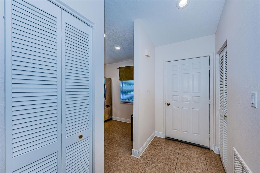 An entryway with tile flooring, a white front door, and louvered closet doors — 1022 BOWSPRIT LANE UNIT 1022, HOLIDAY, FL