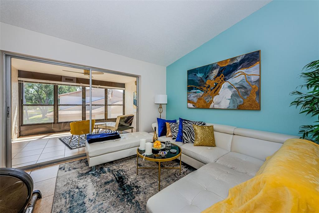 A living room features a white sectional sofa, a blue accent wall, and a sliding door — 1022 BOWSPRIT LANE UNIT 1022, HOLIDAY, FL