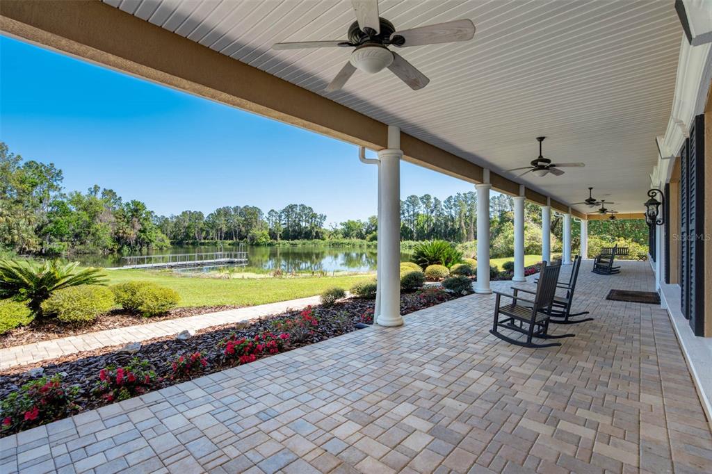 A view through a window shows a lake, a dock, and a rocking chair outside — 701 E 60 HIGHWAY, PLANT CITY, FL
