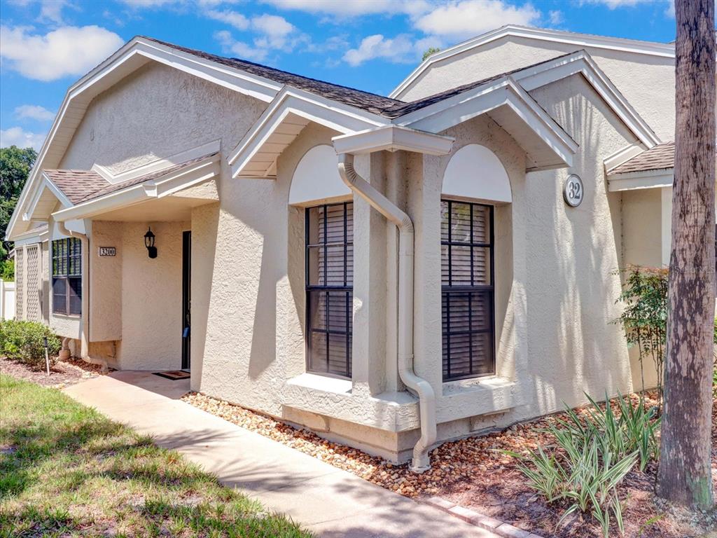 A tan stucco exterior of a single-story residential building with a walkway and downspout — 5100 BURCHETTE ROAD UNIT 3200, TAMPA, FL