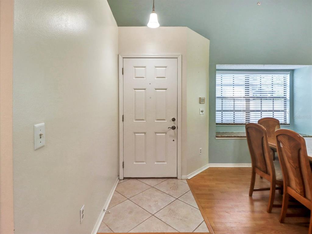 An entryway features a white door, tiled floor, and an adjacent dining area with wood flooring — 5100 BURCHETTE ROAD UNIT 3200, TAMPA, FL