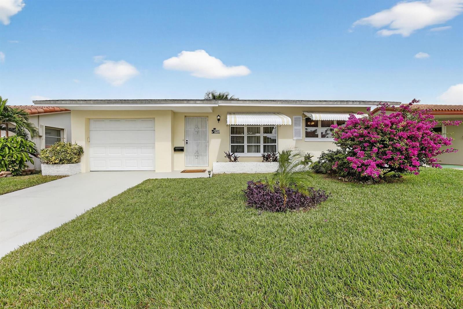 A single-story house with a white garage, light yellow siding, and a vibrant bougainvillea bush — 4305 NW 49th Drive, Tamarac FL 33319, TAMARAC, FL