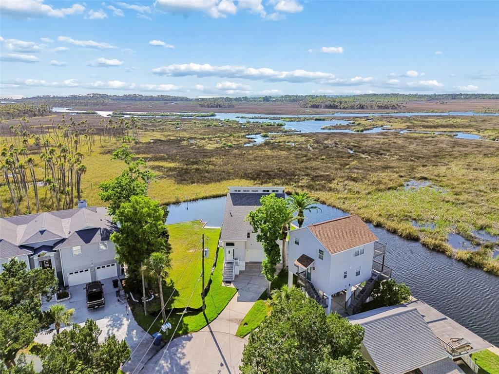 An aerial view shows three houses situated along a waterway bordering a large marshland — 5247 TROPICAL POINT, WEEKI WACHEE, FL