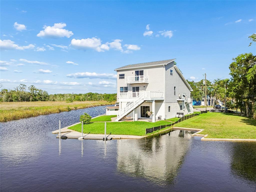 A three-story house with a deck and boat dock sits along a canal — 5247 TROPICAL POINT, WEEKI WACHEE, FL