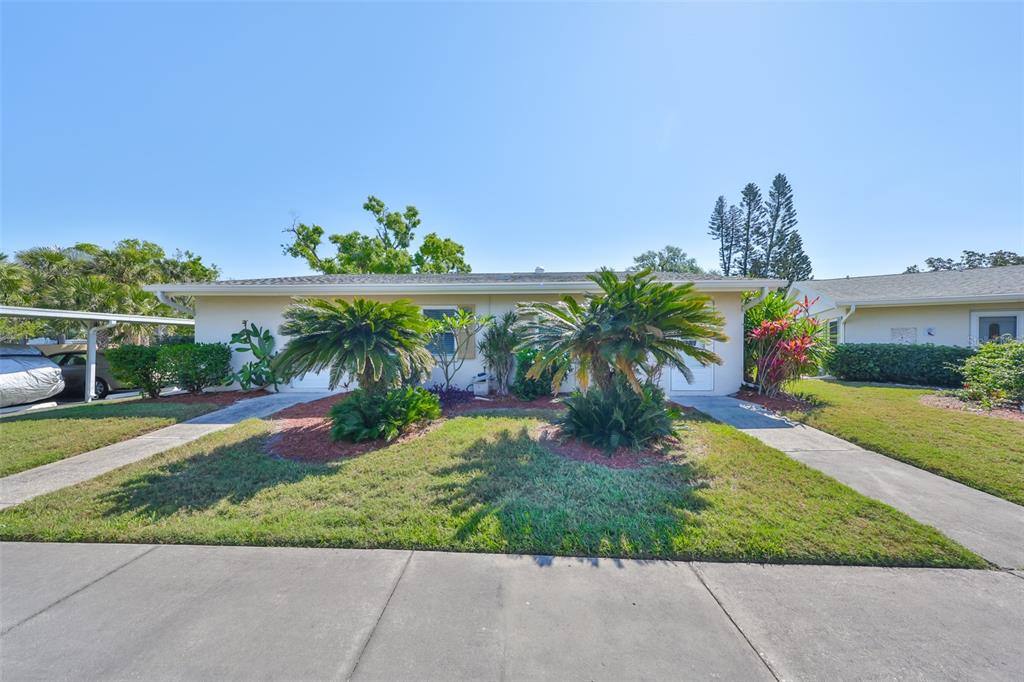 A single-story duplex with a front lawn, two palm trees, and two concrete driveways — 2202 CLUBHOUSE DRIVE UNIT 174, SUN CITY CENTER, FL
