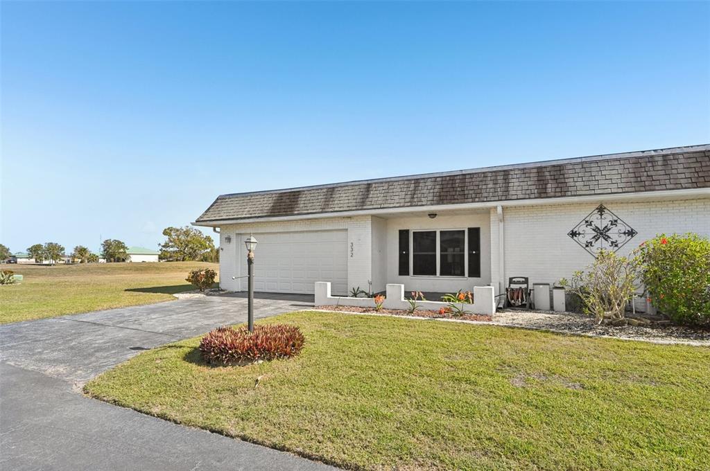 A single-story white brick house with a two-car garage and a paved driveway — 332 CLUB MANOR DRIVE, SUN CITY CENTER, FL