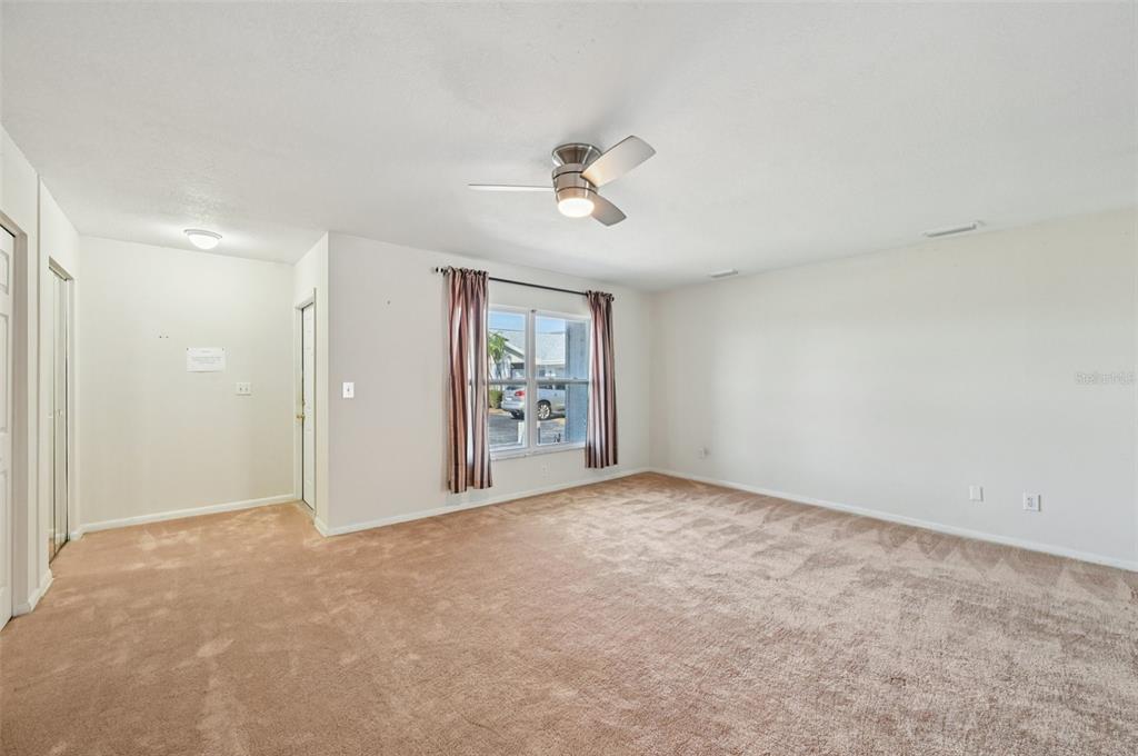 An empty room with beige carpet, a ceiling fan, and a window with curtains — 332 CLUB MANOR DRIVE, SUN CITY CENTER, FL