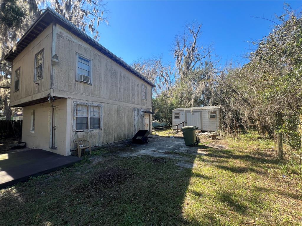 A two-story building with weathered siding stands next to a small shed and yard — 6508 SE 222ND DRIVE, HAWTHORNE, FL