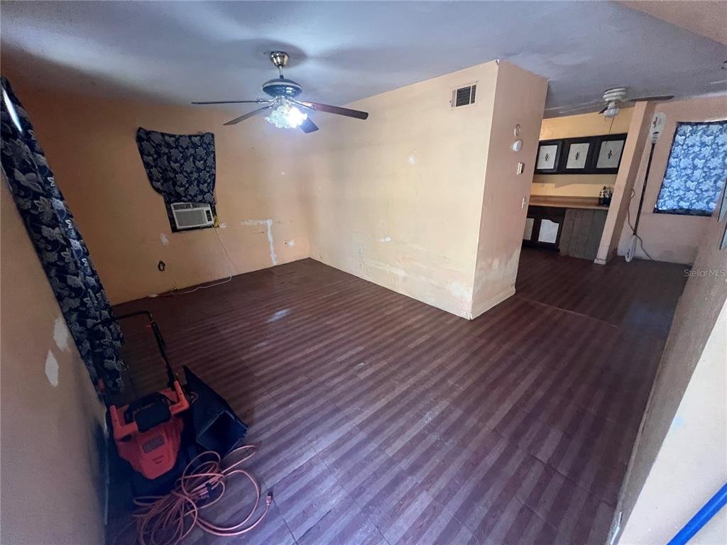 A living room with wood-look flooring, a ceiling fan, and an adjacent kitchen area — 6508 SE 222ND DRIVE, HAWTHORNE, FL