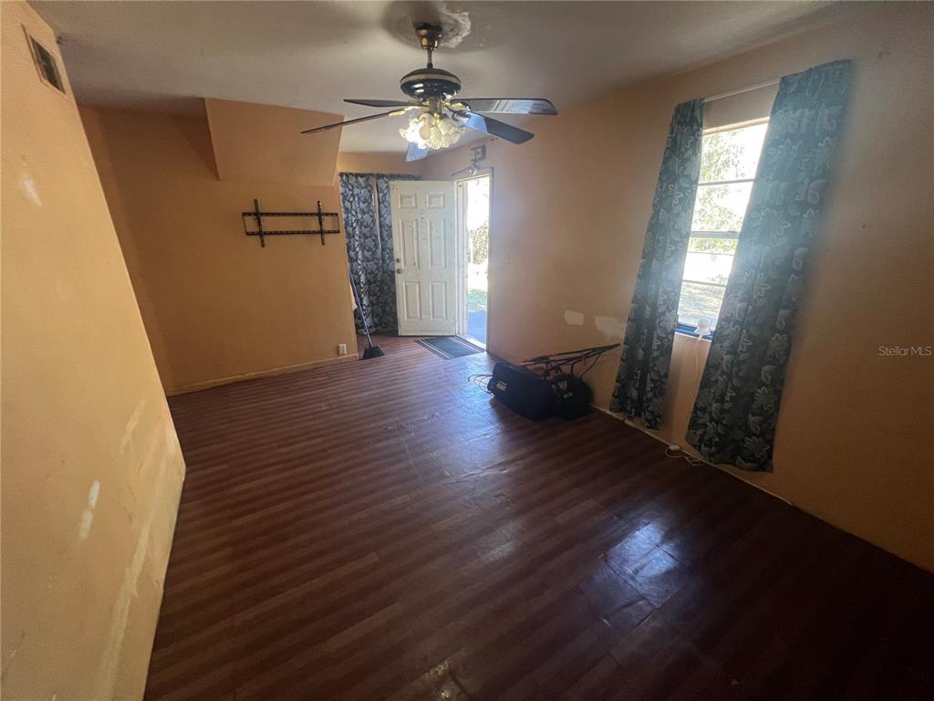 A room with wood-look flooring, tan walls, a ceiling fan, and an open exterior door — 6508 SE 222ND DRIVE, HAWTHORNE, FL