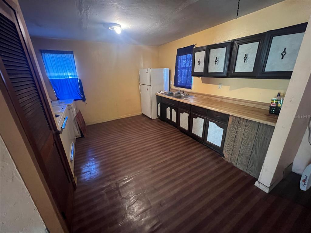 A kitchen features yellow walls, dark cabinets, a wood-look floor, and a white refrigerator — 6508 SE 222ND DRIVE, HAWTHORNE, FL