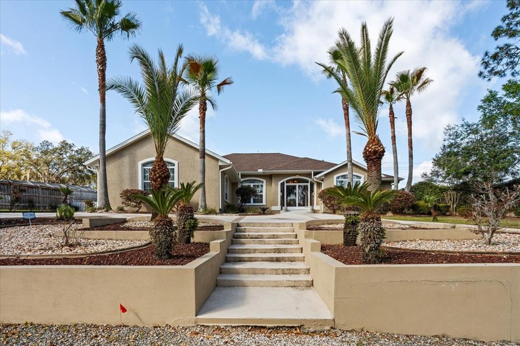 A single-story house with a terraced front yard, concrete stairs, and several palm trees — 196 NW CLUBVIEW CIRCLE, LAKE CITY, FL