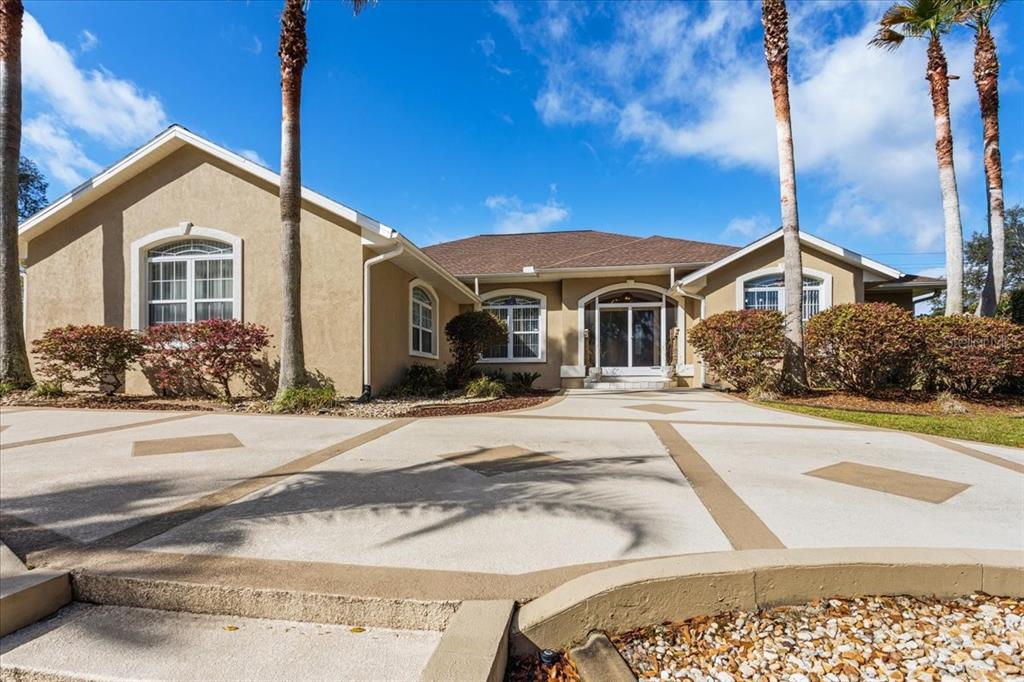 A tan single-story house with a decorative concrete driveway and palm trees in the front — 196 NW CLUBVIEW CIRCLE, LAKE CITY, FL