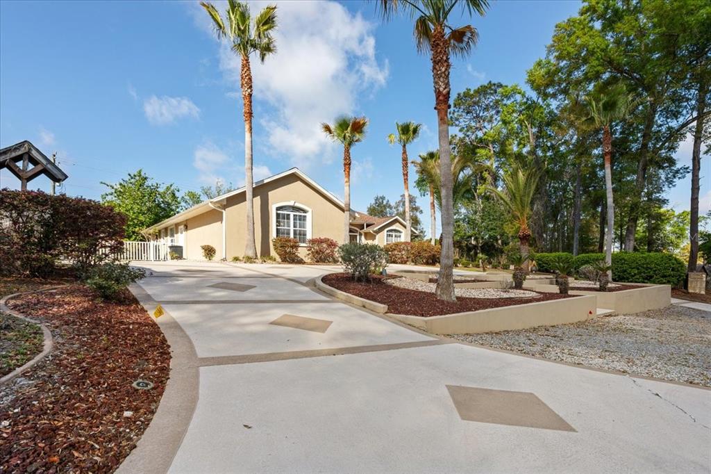 A tan house with a decorative concrete driveway and several palm trees in the front yard — 196 NW CLUBVIEW CIRCLE, LAKE CITY, FL