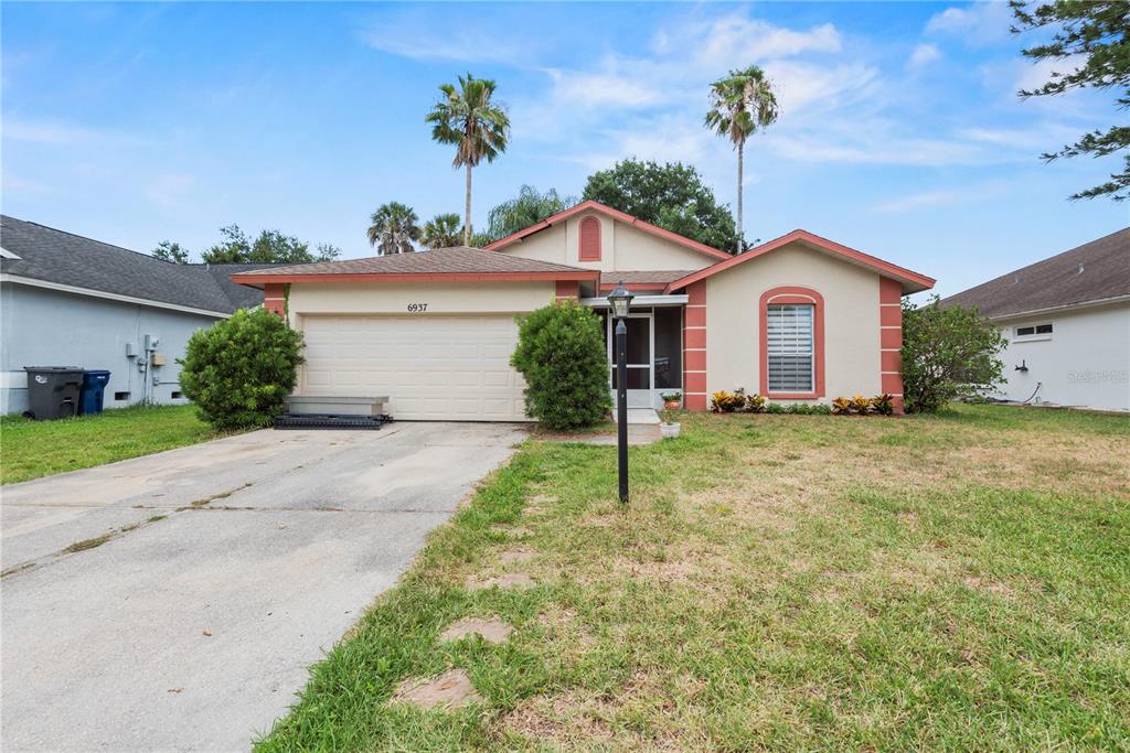 A single-story house with a beige exterior, red trim, a two-car garage, and palm trees — 6937 42ND COURT E, SARASOTA, FL