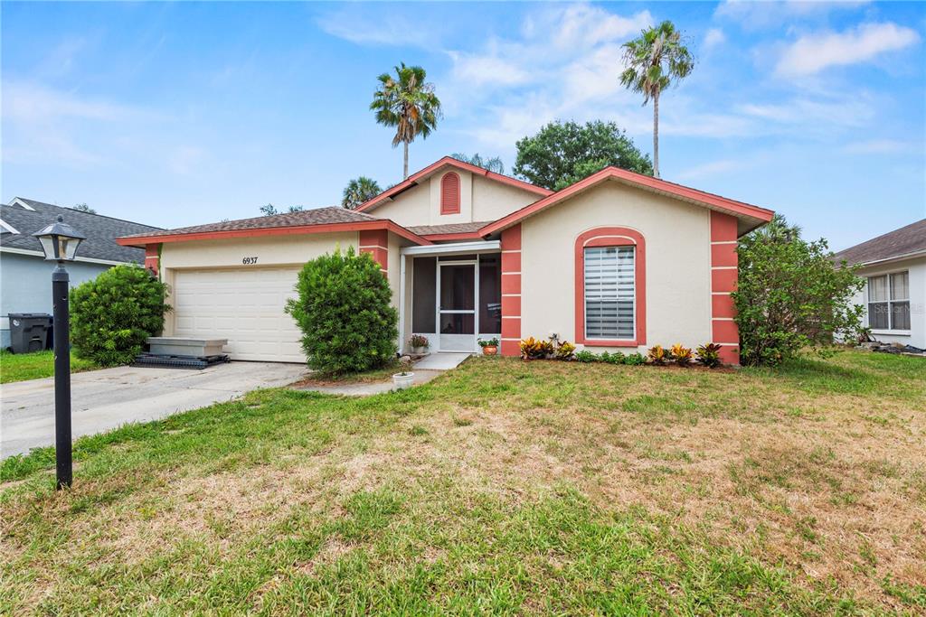 A single-story house with a beige stucco exterior, red trim, and a two-car garage — 6937 42ND COURT E, SARASOTA, FL