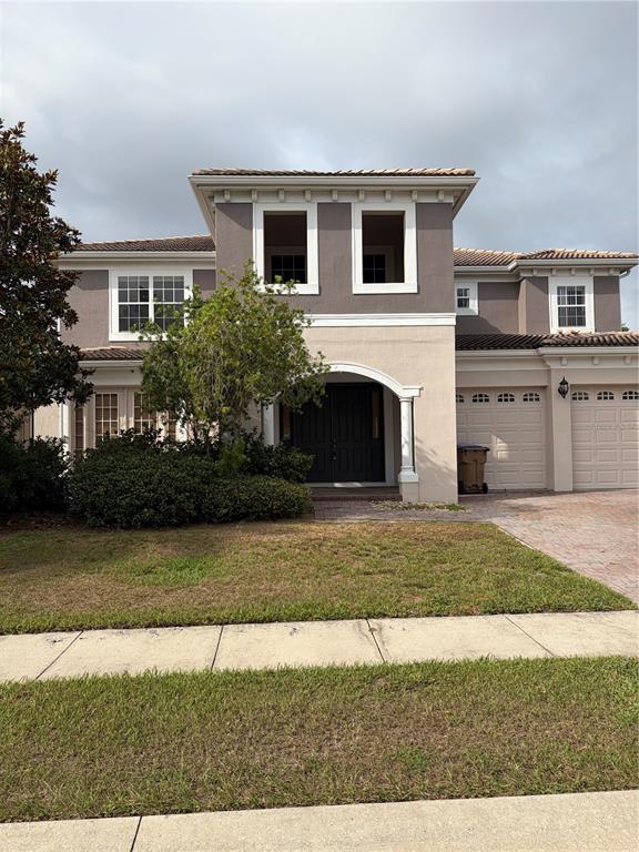 A two-story house with a beige and gray exterior, arched entryway, and two-car garage — 3822 SHOREVIEW DRIVE, KISSIMMEE, FL