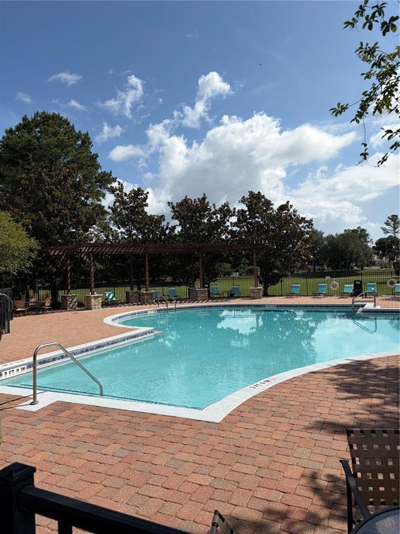 An outdoor swimming pool with a brick deck and a wooden pergola under a blue sky — 3822 SHOREVIEW DRIVE, KISSIMMEE, FL
