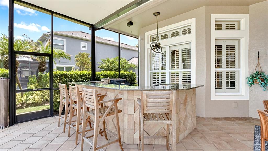 A covered patio features a stone-tiled outdoor bar with wooden stools and screened walls — 4911 PARKVIEW DRIVE, ST CLOUD, FL