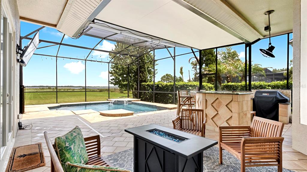 A covered patio features a pool, outdoor bar, fire pit, and a screened-in view — 4911 PARKVIEW DRIVE, ST CLOUD, FL