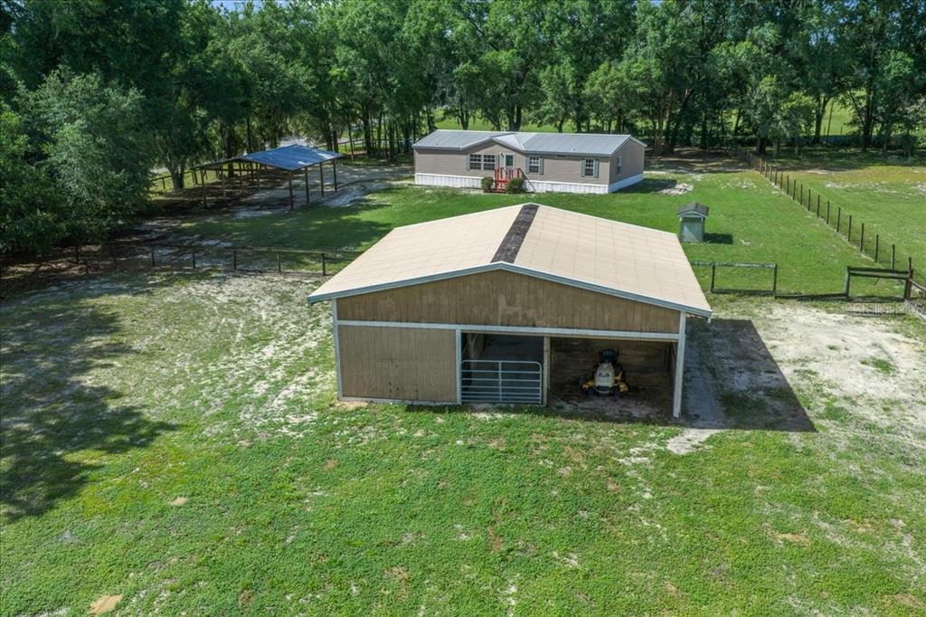 An aerial view shows a barn, a mobile home, and a carport on a grassy lot — 3551 NE 120TH STREET, ANTHONY, FL