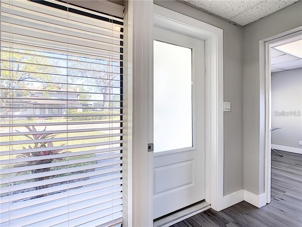 A room features a window with blinds, a white door with frosted glass, and flooring — 1501 W FAIRBANKS AVENUE, WINTER PARK, FL