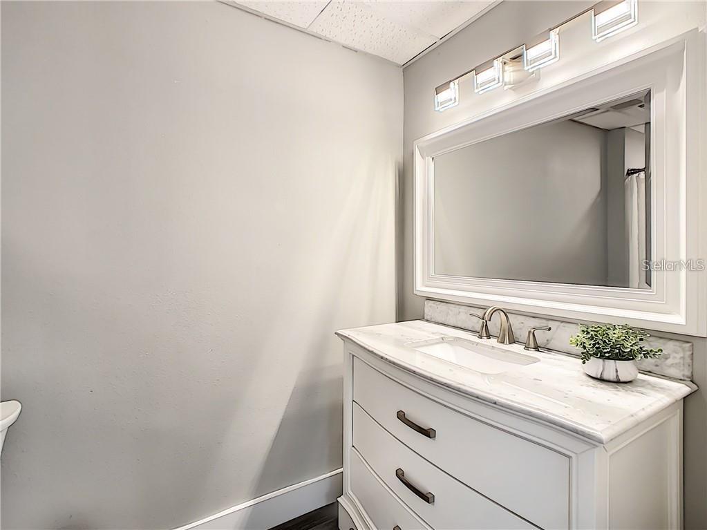 A bathroom features a white vanity with a marble countertop, a mirror, and light fixtures — 1501 W FAIRBANKS AVENUE, WINTER PARK, FL