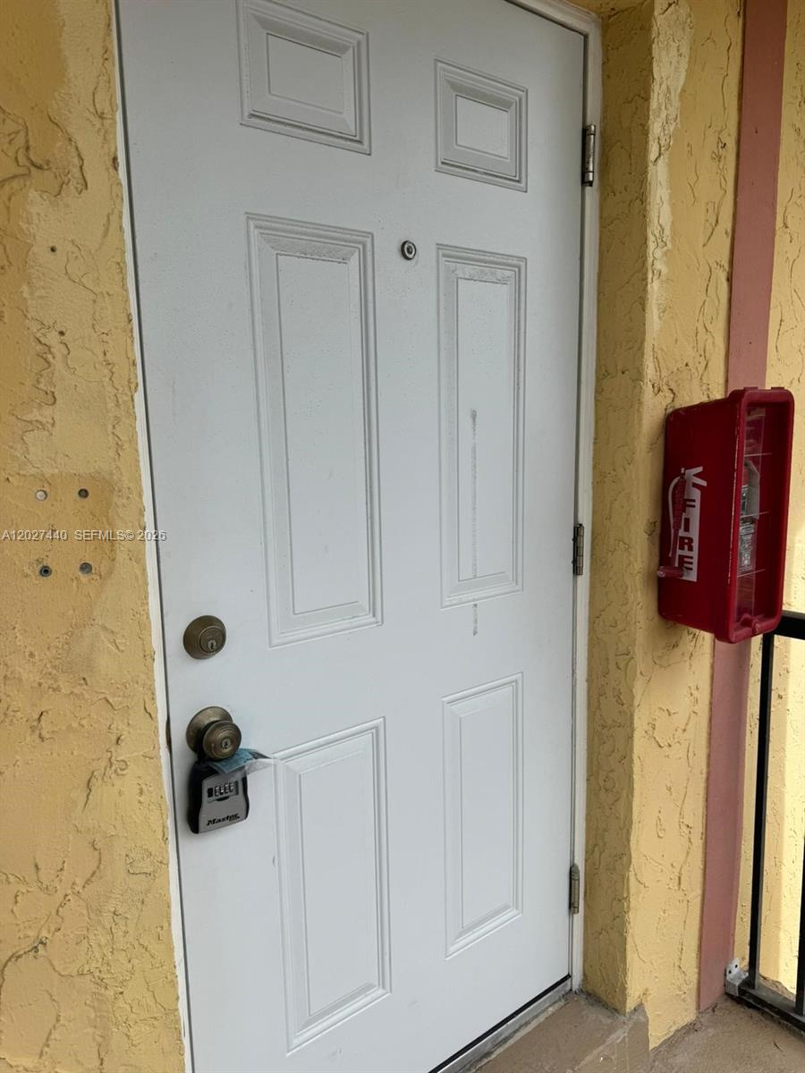 A white exterior door with a lockbox and a red fire extinguisher box nearby — 2854 NW 55th Ave # 2B, Lauderhill FL 33313, LAUDERHILL, FL