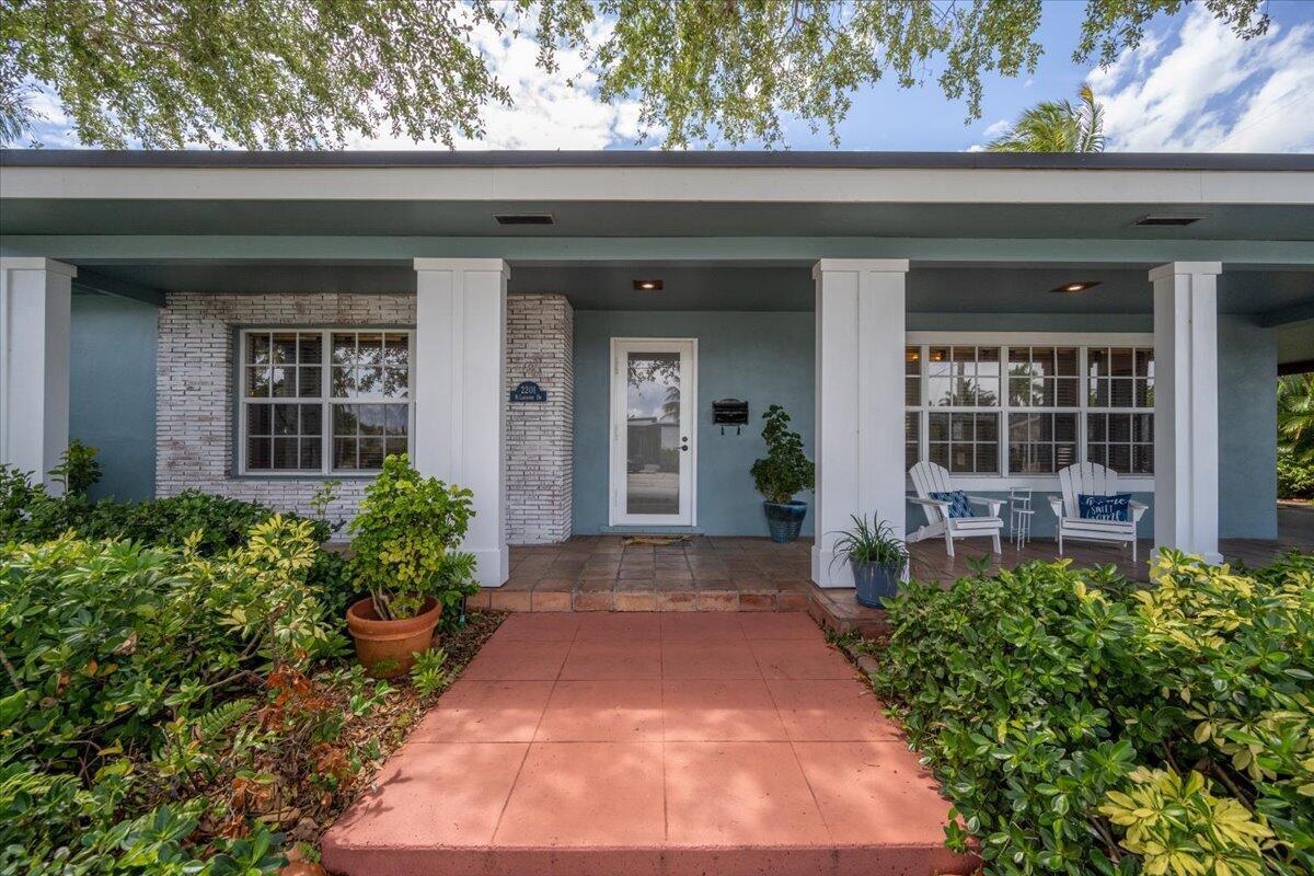 The front exterior of a blue house features a tiled walkway, white columns, and windows — 2201 N Lakeside Drive, FL 33460, FL