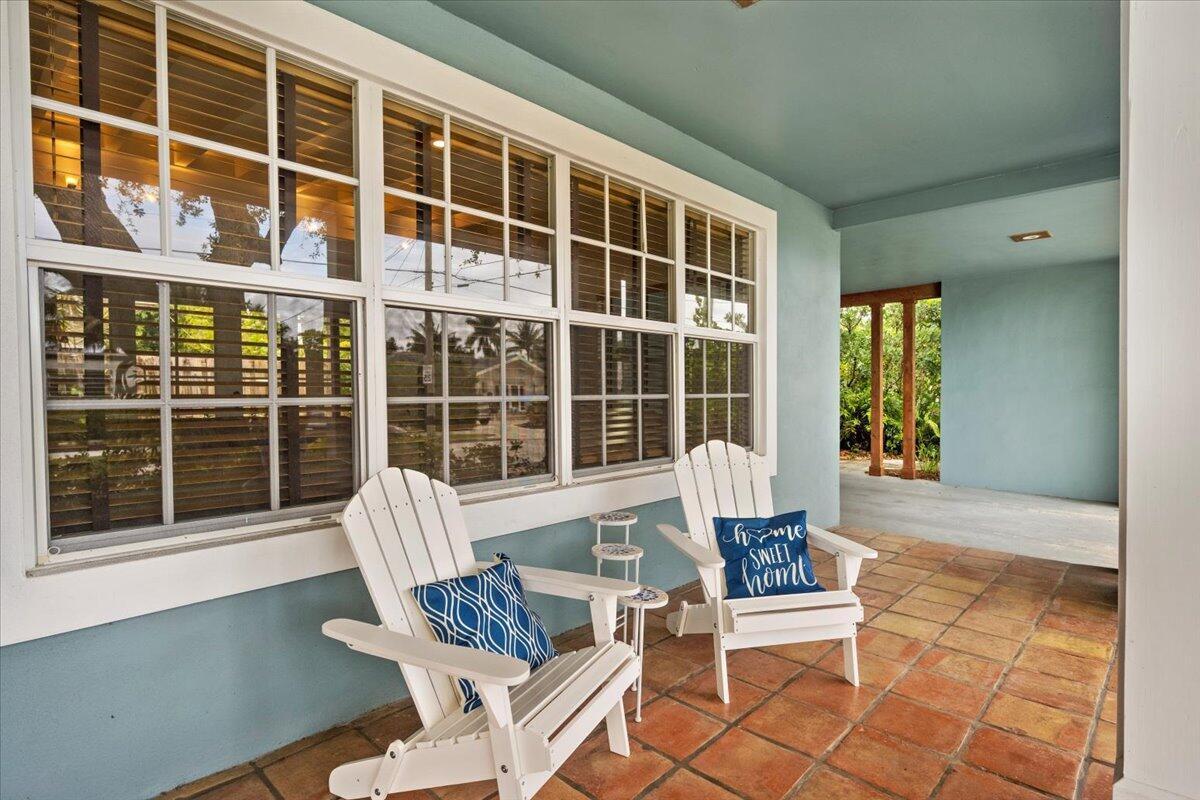 A covered porch features white Adirondack chairs on a terracotta tile floor — 2201 N Lakeside Drive, FL 33460, FL