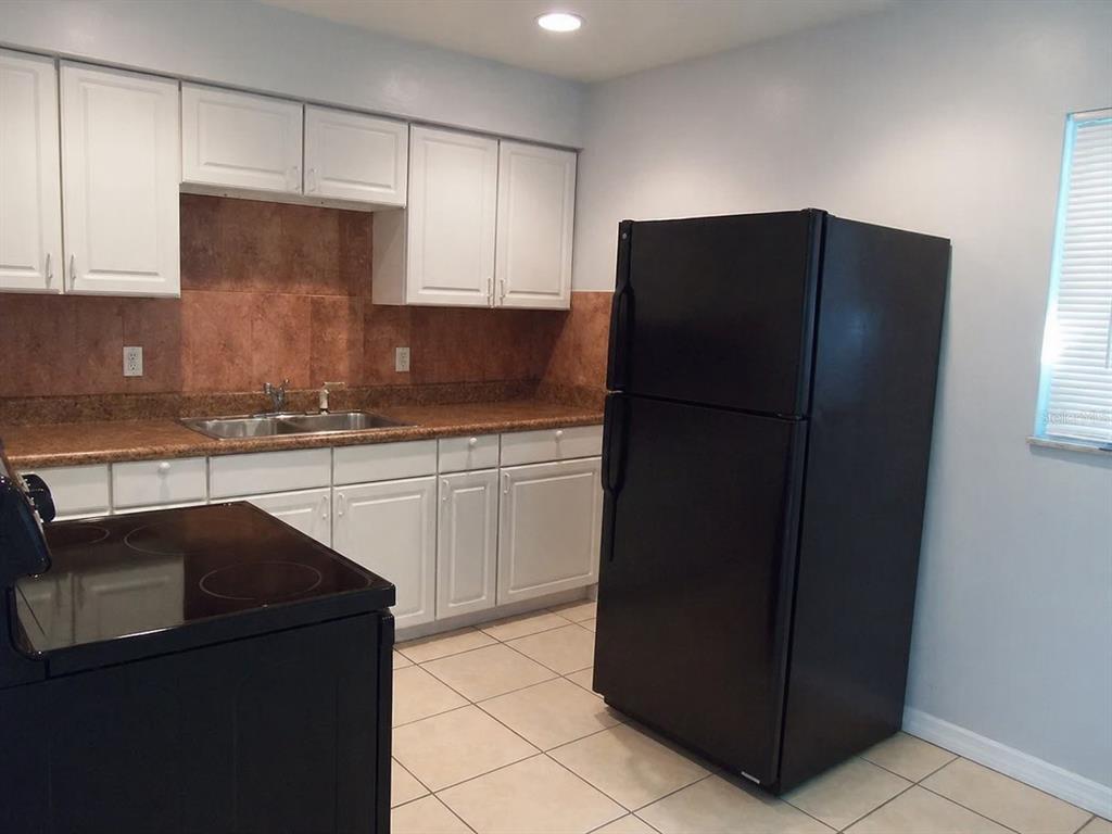 A bathroom features a white tub, a dark wood vanity, and brown tiled walls — 1427 PLEASANT PLACE, LAKELAND, FL