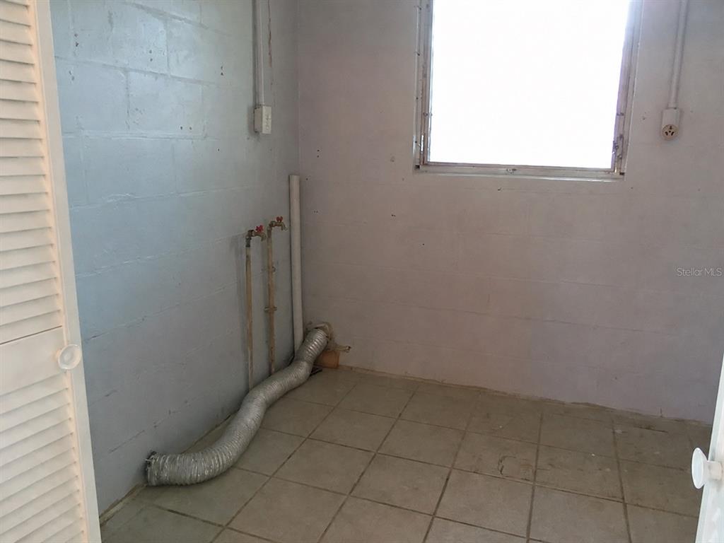 A room with light gray walls, beige tile flooring, a glass-paneled door, and louvered closet doors — 1427 PLEASANT PLACE, LAKELAND, FL